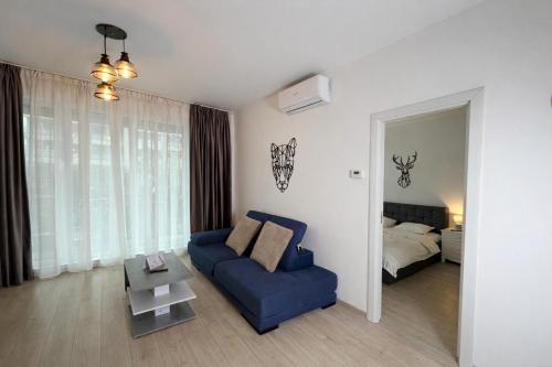 a living room with a blue couch and a bed at Sphynx Apartment Pipera in Voluntari
