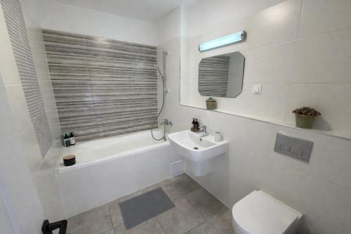 a white bathroom with a toilet and a sink at Sphynx Apartment Pipera in Voluntari