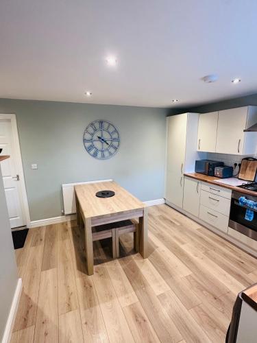 a kitchen with a wooden table and a clock on the wall at Barber House, Hoyland with two allocated parking spaces in Hoyland Nether