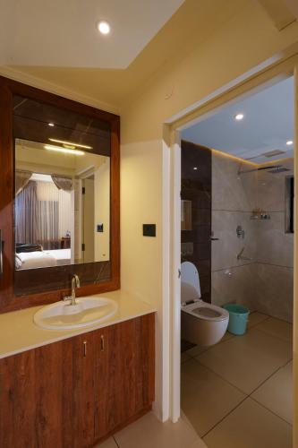 a bathroom with a sink and a toilet and a mirror at Adonna Beach Resort in Alleppey