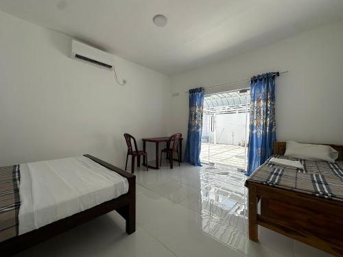 a bedroom with a bed and a table and a window at Andrella Rest House in Mannar