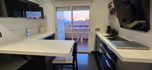 a kitchen with a white counter top and a table at Espectacular ático en 1°linea playa in Rota