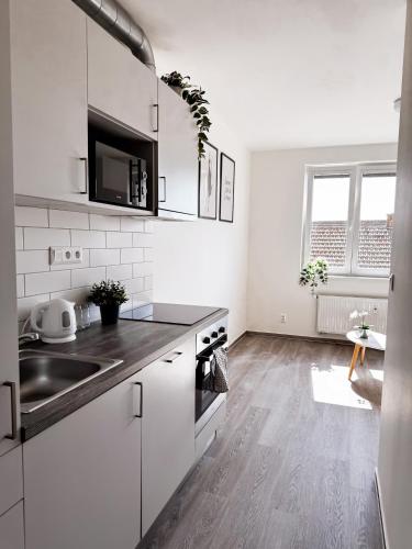 a white kitchen with white cabinets and a sink at District B Apartments in Brno