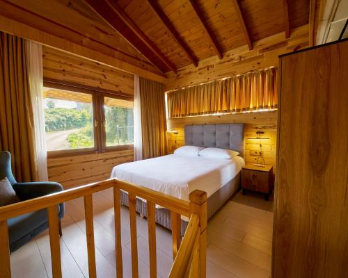 a bedroom in a log cabin with a bed and a window at Sarı Köşk Hotel in Rize