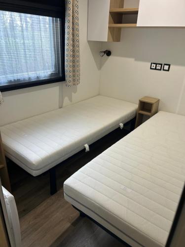 a small room with two beds and a window at Mobilhome 592 FUNPASS NON INCLUS in Gastes
