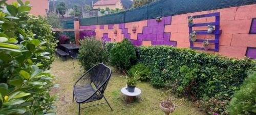 a chair sitting in a garden with a wall at Hospedaje Villa Blas in Redondela