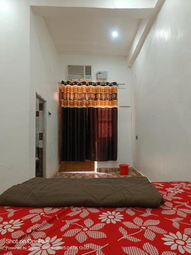 a bedroom with a bed and a window with a red blanket at Kaushlendra Bhawan in Ayodhya