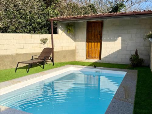 a swimming pool in front of a house with a bench at A Casa da aldea de Iria in Padrón