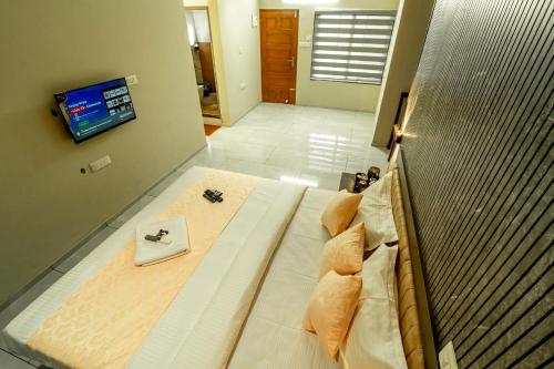 ein großes Bett in einem Zimmer mit einem Fernseher an der Wand in der Unterkunft Zoho Suites in Kochi
