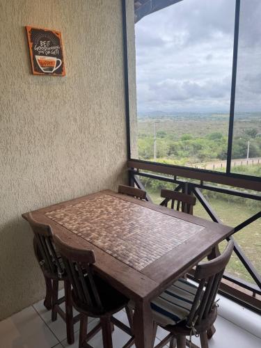 a wooden table and chairs in a room with a window at Flat com linda vista no Monte Castelo in Sairé