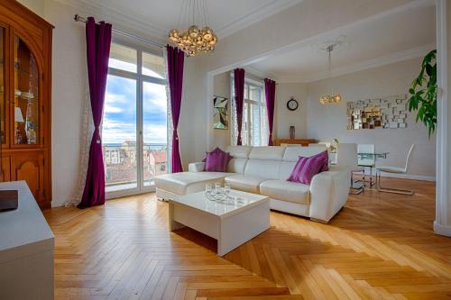 een woonkamer met een witte bank en een tafel bij Appartement Vaste Horizon - LRA Cannes in Cannes