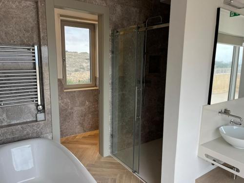 a bathroom with a shower and a tub and a sink at Sunset Edge Villa - 77 Retreats in Għajn Tuffieħa