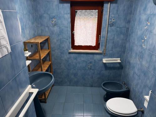 a blue tiled bathroom with a toilet and a sink at La Pennichella in Agerola