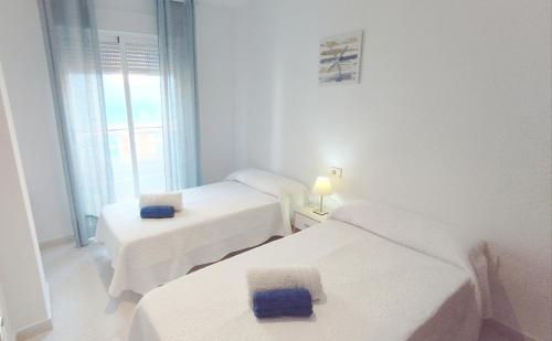 a white room with two beds and a window at Piso 3 habitaciones en Pescadores, 6 in Peniscola