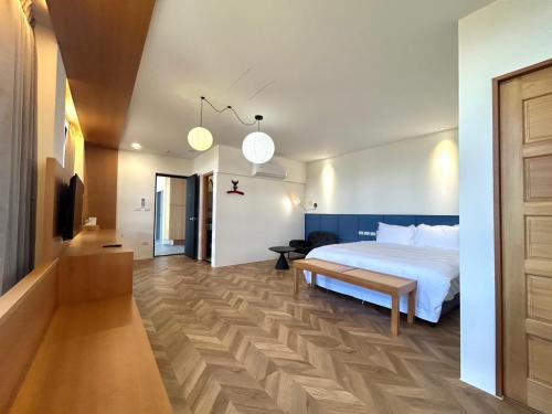 a bedroom with a white bed and a wooden floor at Yutian B&B in Zhuangwei