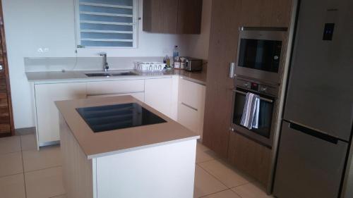 a kitchen with white cabinets and a stainless steel refrigerator at L'Escale 3 bedrooms Sea View and Beachfront Suite by Dream Escapes in Tamarin