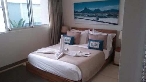a bedroom with a bed with white sheets and blue pillows at L'Escale 3 bedrooms Sea View and Beachfront Suite by Dream Escapes in Tamarin