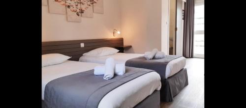 two beds in a hotel room with white pillows at Auberge de la Poterne in Moncontour