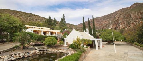 a house with a pond in front of a mountain at Montagu Little Sanctuary - Hot Spring Access at reduced price in Montagu