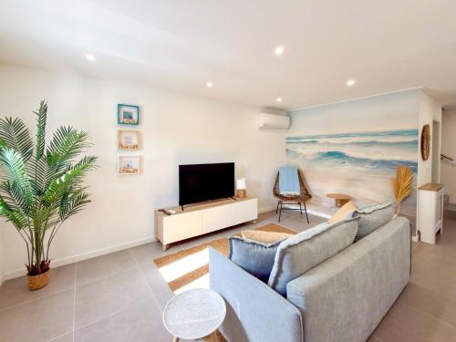a living room with a couch and a flat screen tv at Alma do Mar - Alma Nossa in Montijo