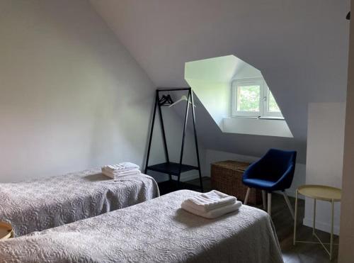 a room with two beds and a window and a chair at La buanderie du château in Le Boulay