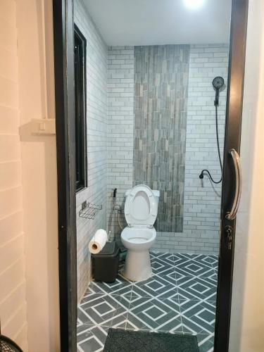 a bathroom with a toilet with a tile floor at Ingphai Homestay in Suratthani