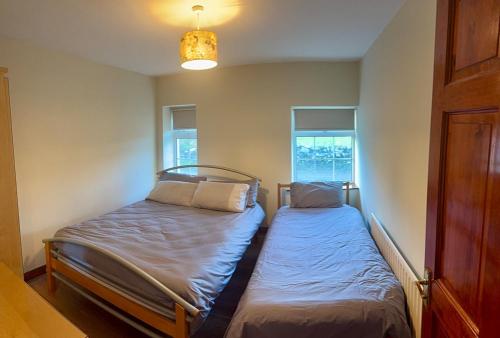 two beds in a small room with two windows at Beachfront Cottage - 3 bedrooms in Clogherhead