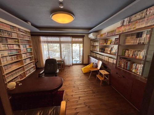 a library with bookshelves and a desk and a table at 離れの宿 かぶろの庭 離れの宿 KuRA in Matsukawa