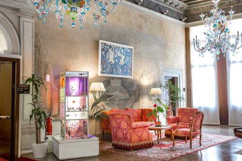 a lobby with chairs and a table and a chandelier at Ruzzini Palace Hotel in Venice
