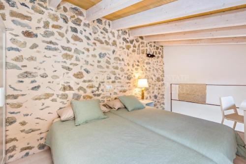a bedroom with a bed with a stone wall at CAN REGALAT - Casa amb piscina a Artà in Artá