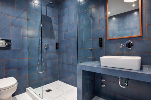 a blue tiled bathroom with a toilet and a sink at Colors Urban Hotel Thessaloniki in Thessaloniki