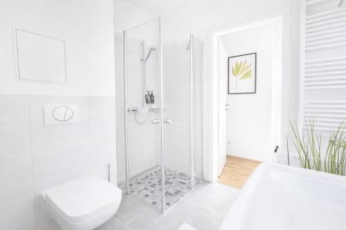 a white bathroom with a shower and a toilet at Larooms Merseburg - Apartment CS01 - 3 Zimmer, 7 Betten, 2 Bäder, 2 Parkplätze, Balkon & Aufzug in Merseburg