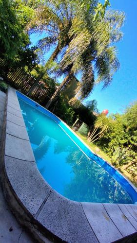 a swimming pool with blue water and palm trees at margarita in Sauce Viejo