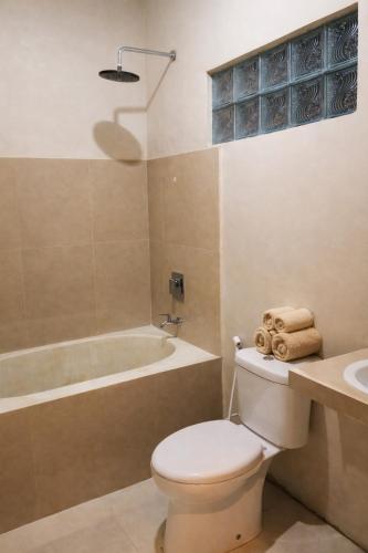 a bathroom with a toilet and a tub and a sink at GGuesthouse in Kuta Lombok