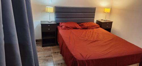 a bedroom with a bed with orange sheets and two night stands at Victoriano in La Rioja