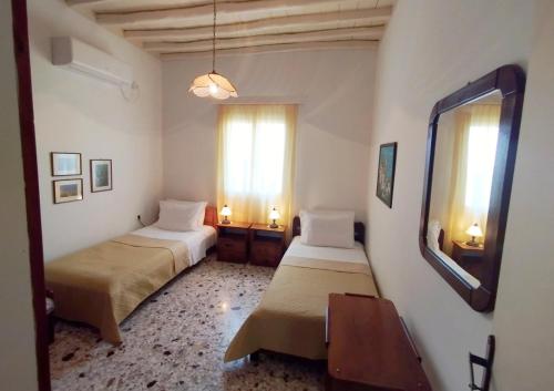 a room with two beds and a table and a window at Almond trees house in Órmos Aiyialís