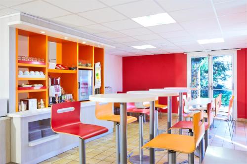 une salle à manger avec des tables et des chaises colorées dans l'établissement Premiere Classe Versailles - Saint Cyr L'ecole, à Saint-Cyr-lʼÉcole