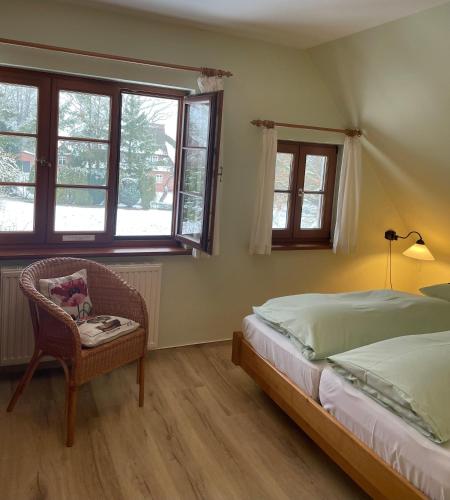 a bedroom with a bed and a chair and windows at Landhaus Susewind in Ahrenshoop