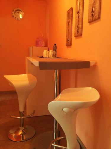 a kitchen with a counter and two white stools at Ferienwohnung Grimmer in Weil am Rhein