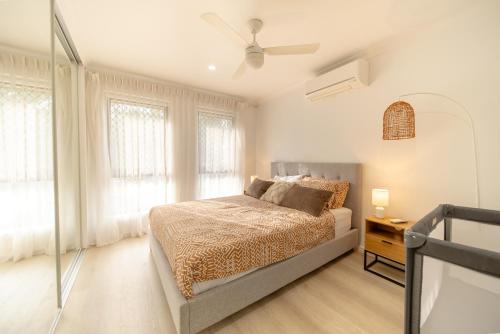 a bedroom with a bed and a ceiling fan at 3BR Little Coastal Boho Home - Neverending Summer Fun near Themeparks & close to M1 exit in Pimpama
