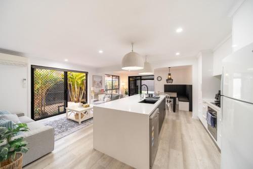 an open kitchen and living room with white appliances at 3BR Little Coastal Boho Home - Neverending Summer Fun near Themeparks & close to M1 exit in Pimpama