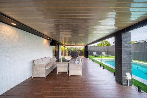 a patio with a couch and a table and a pool at 3BR Little Coastal Boho Home - Neverending Summer Fun near Themeparks & close to M1 exit in Pimpama
