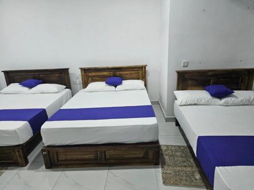 three beds in a room with blue and white sheets at Nil Manel Tourist in Anuradhapura