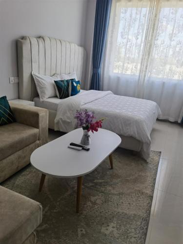 a living room with a bed and a table with flowers at Pride homes in Marimbeti