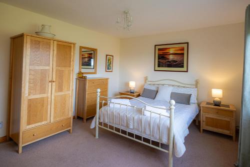 a bedroom with a bed and a cabinet and two lamps at Owlswood Lodge in Orkney
