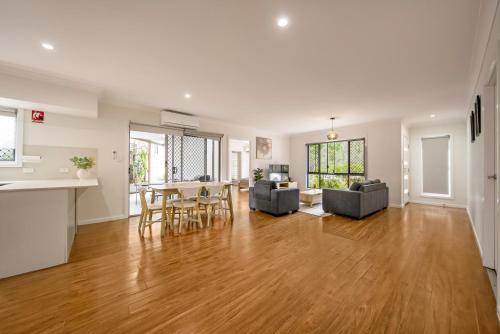 an empty living room with a hardwood floor and a kitchen at 3BR Coomera Duplex 2- Cute & Cosy Home Close to Theme Park in Gold Coast