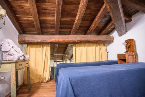 a bedroom with a blue bed and wooden ceilings at Al Castello di Leprignano in Capena