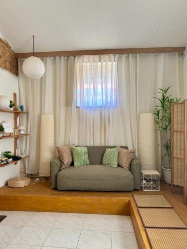 a living room with a couch in front of a window at Fika Siargao - Cozy Island Home in General Luna in General Luna