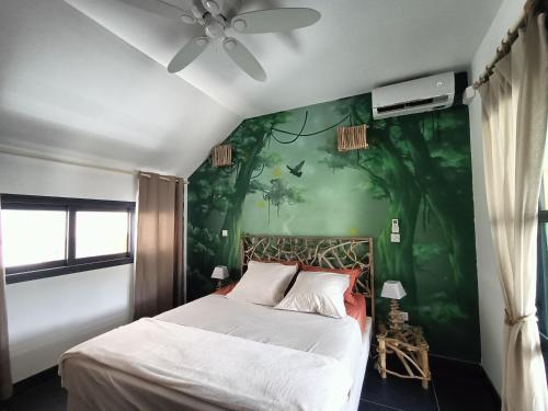 a bedroom with a bed with a green wall at La Cabane du lagon atypique et accès à la plage in La Saline les Bains