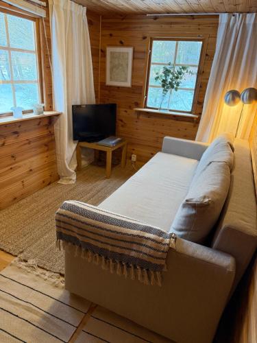 a living room with a couch and a television at Skogsnära boende i Ludvigsborg in Ludvigsborg